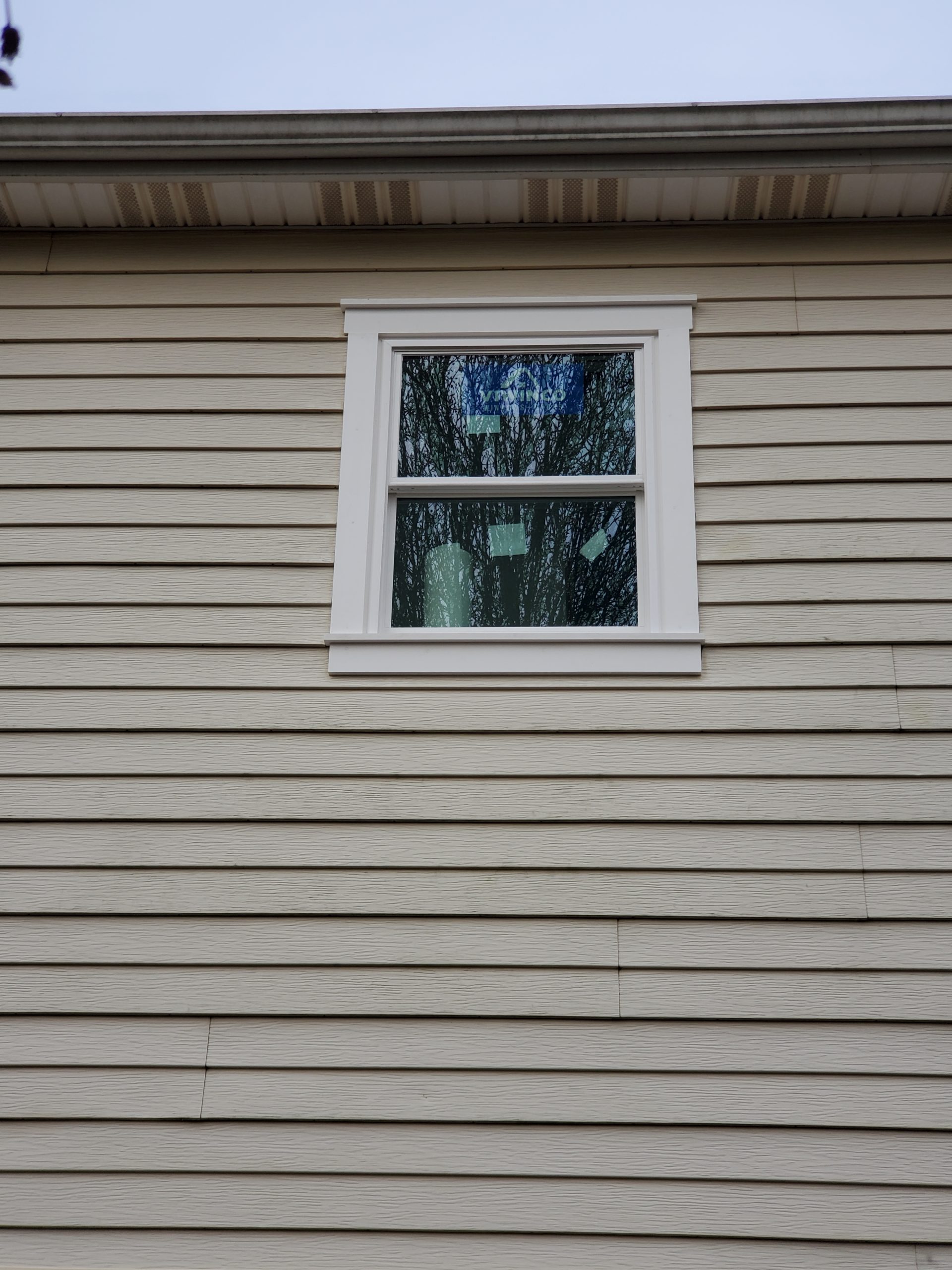 New white vinyl replacement window set in gray clapboard siding