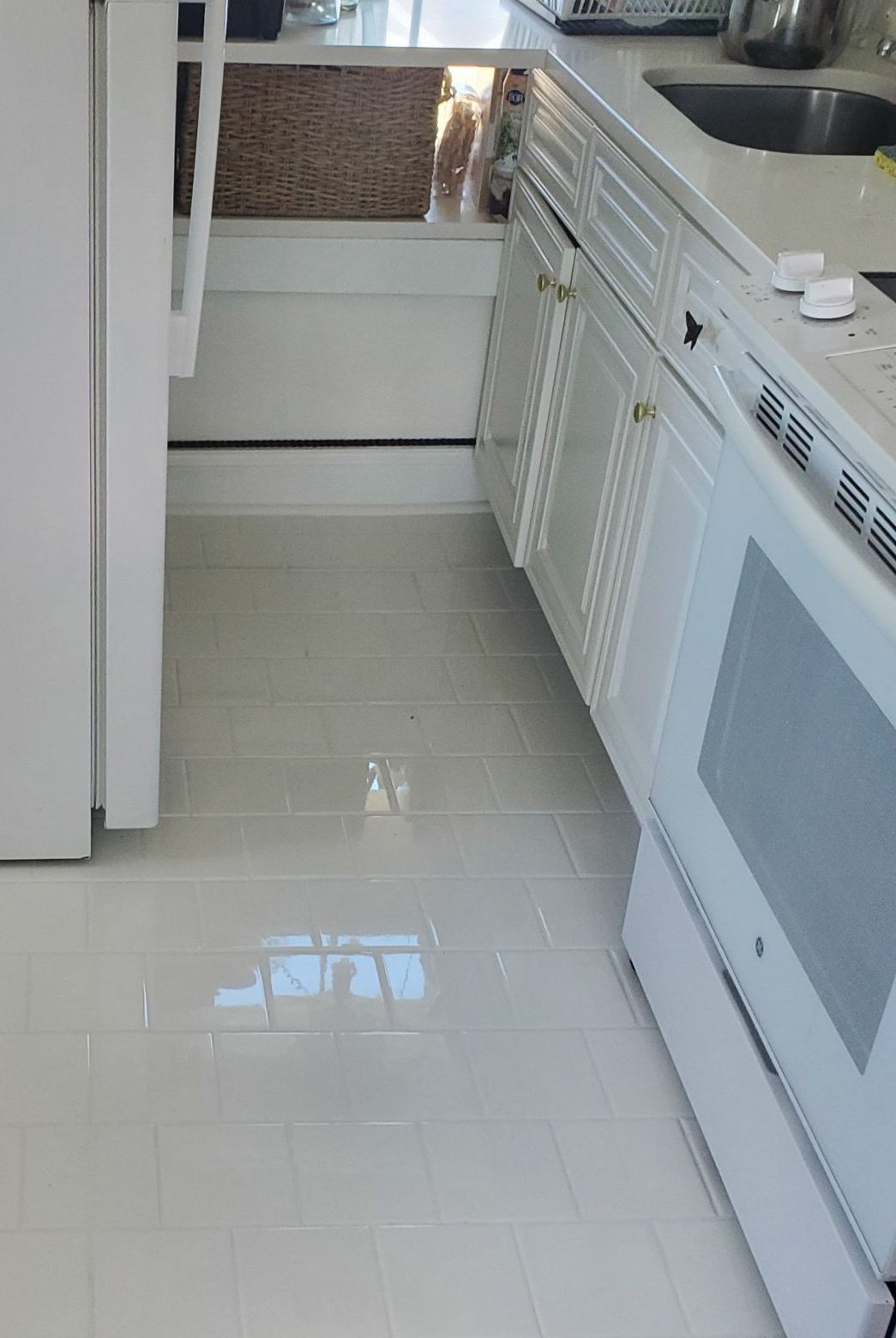 Kitchen floor with large light-gray tile beside white cabinets and appliances