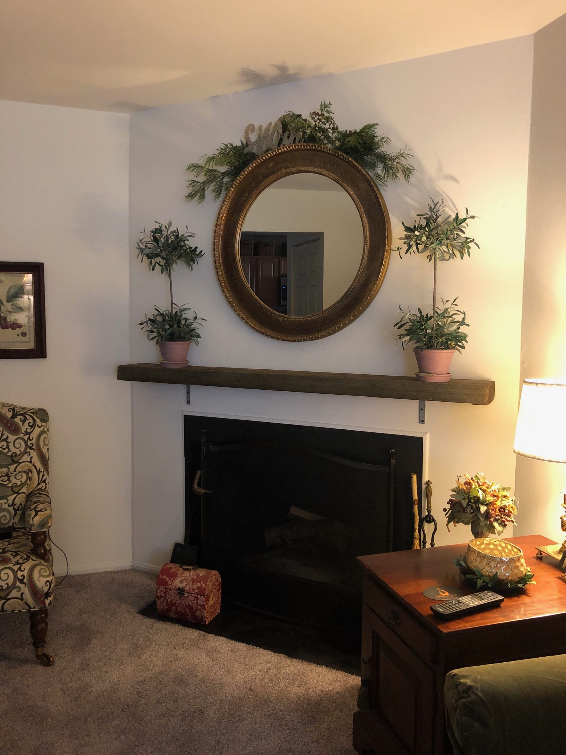 Living room fireplace with a reclaimed wood mantel and round gilt mirror