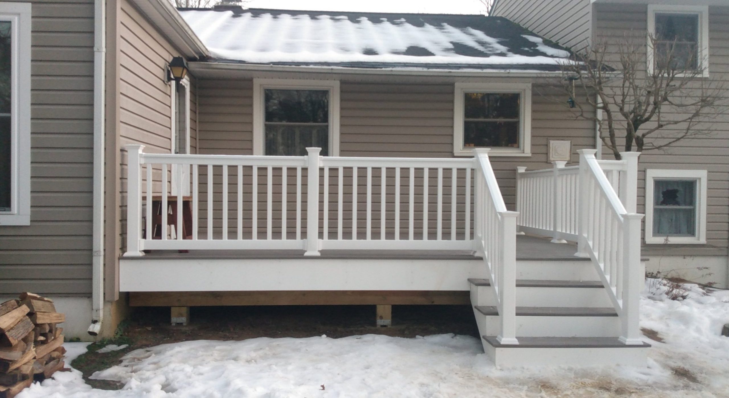 Home exterior with a new white deck and railing, photographed in winter