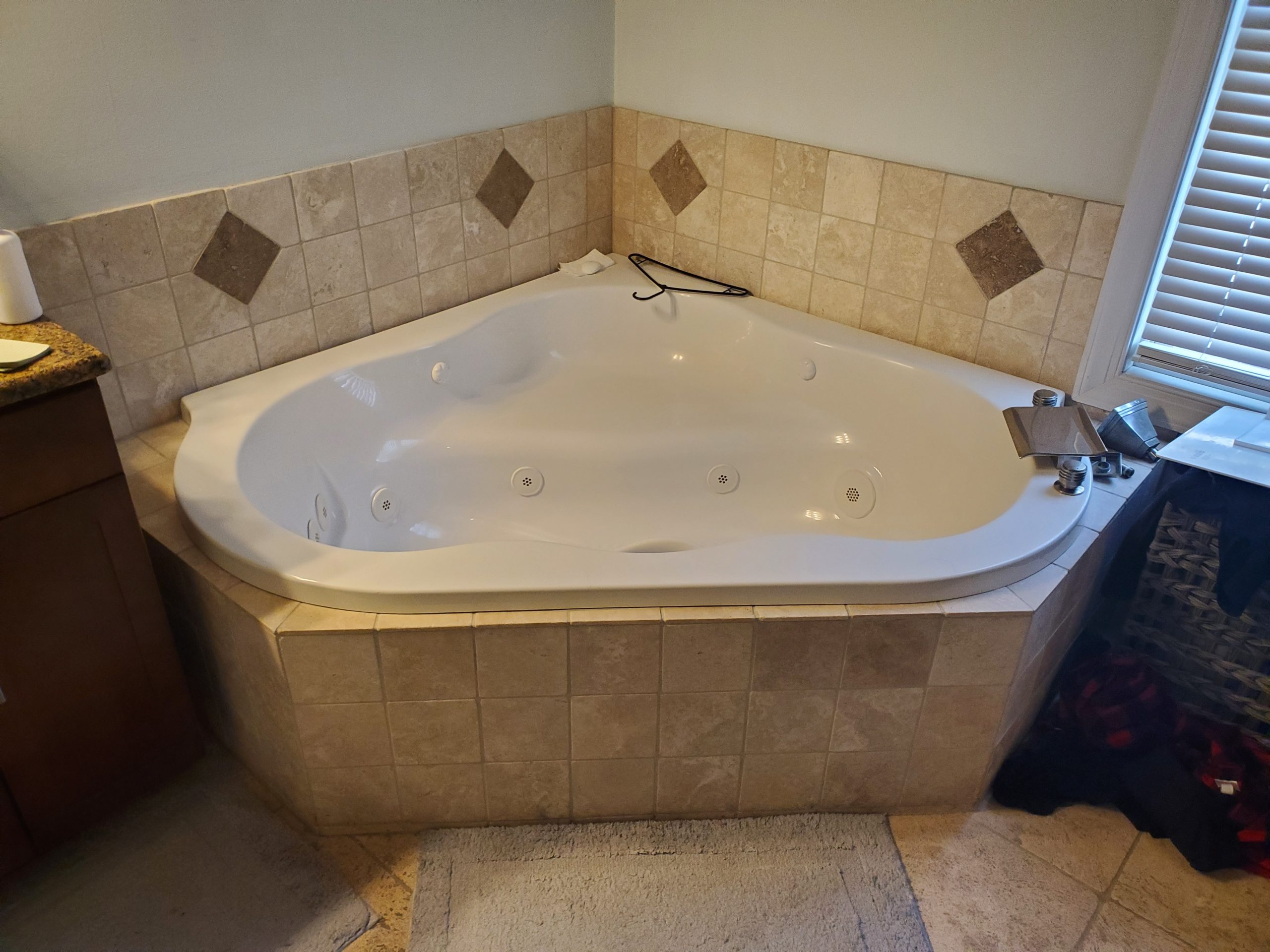 Corner jetted soaking tub set into a tiled deck surround