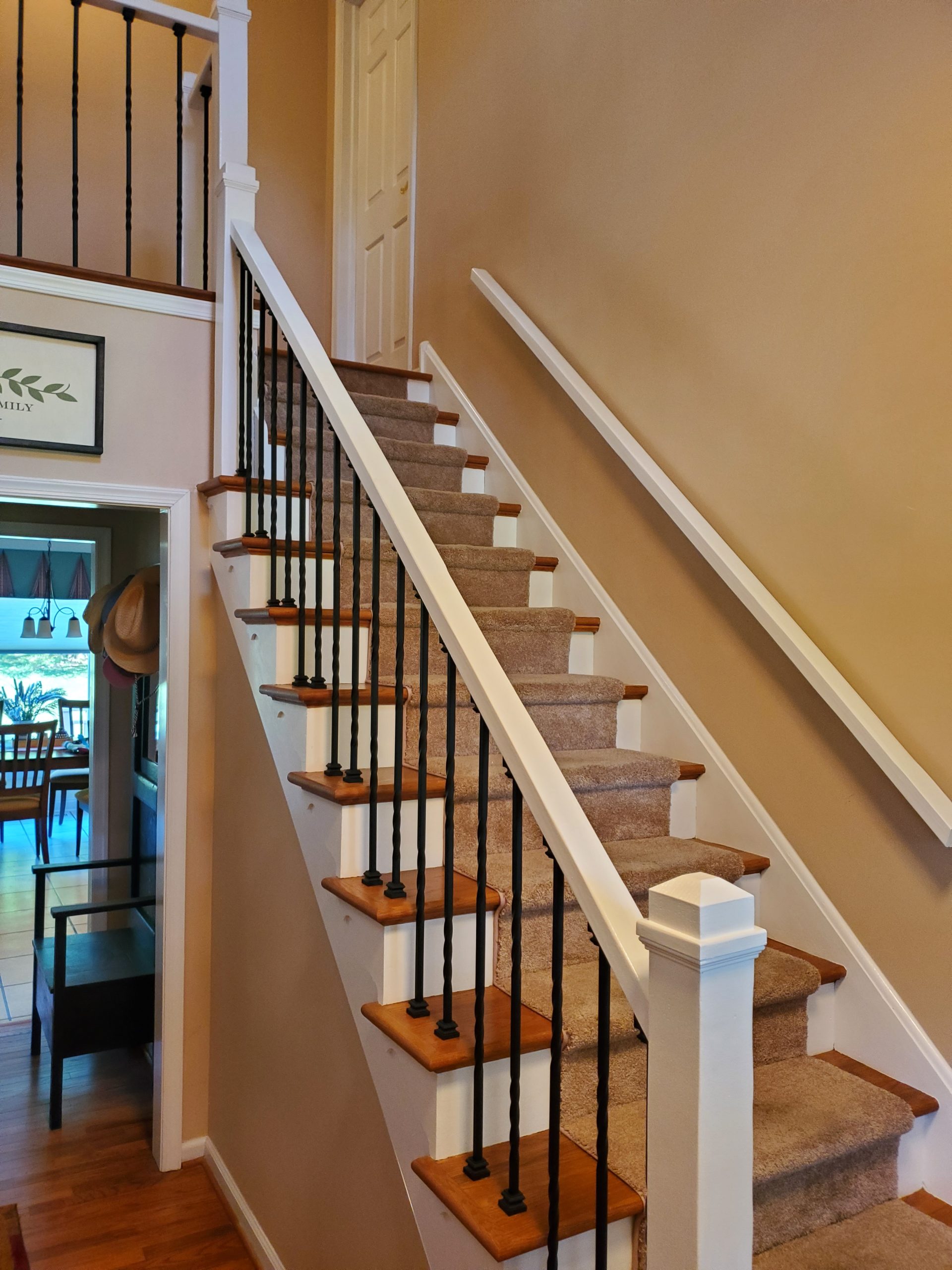 Refinished staircase with wood treads, white risers, and black metal balusters