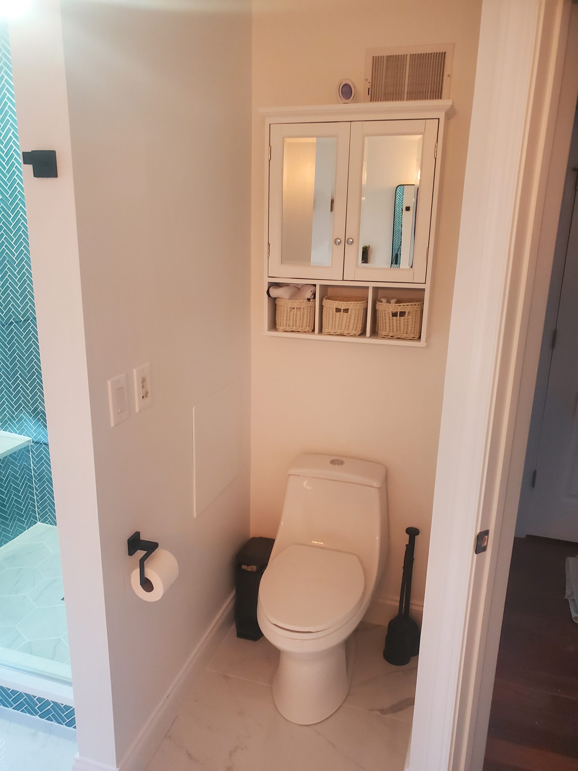 Small bathroom with teal herringbone tile and a mirrored medicine cabinet