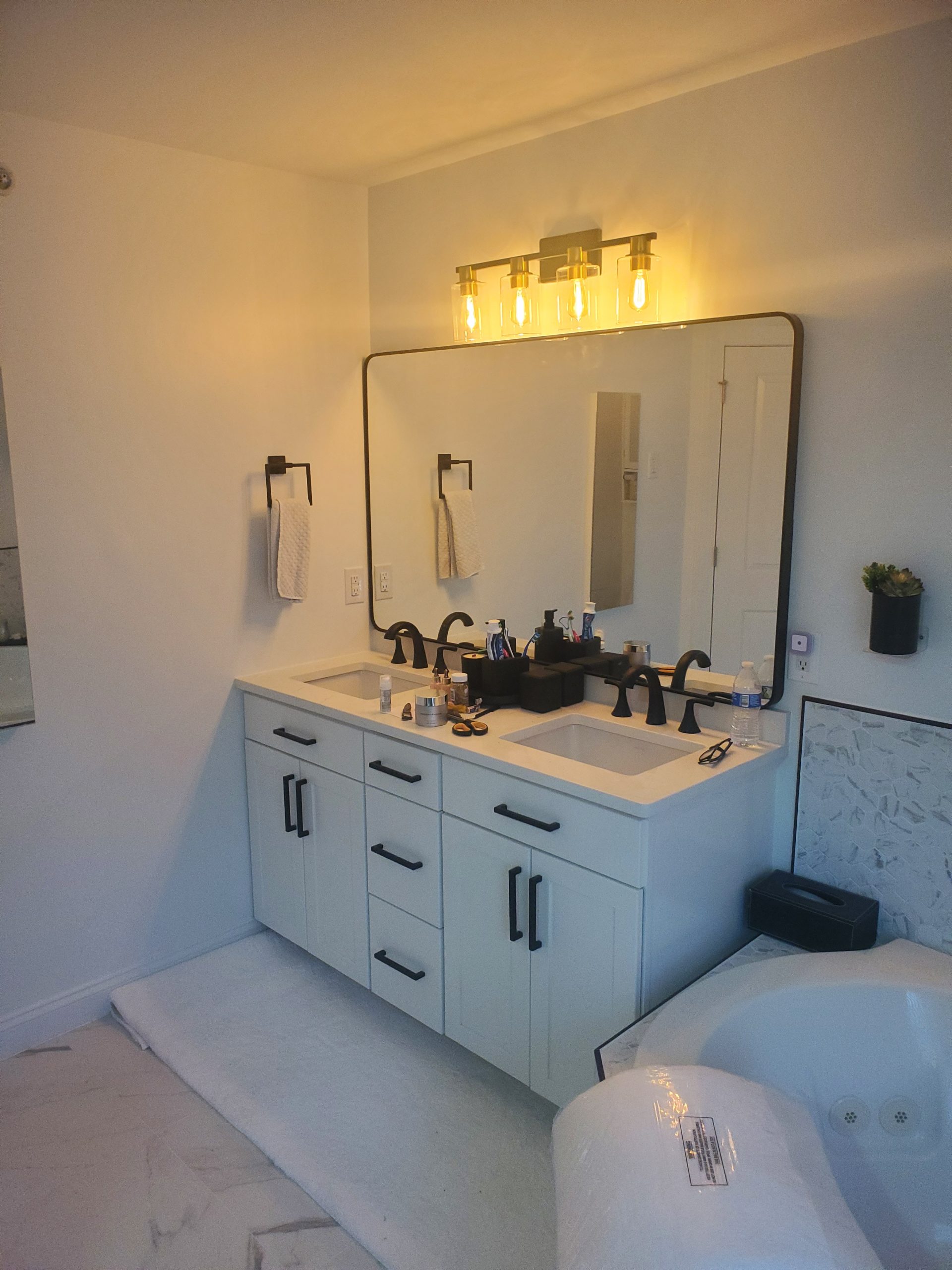 Remodeled bathroom vanity with white cabinets, stone top, and black fixtures