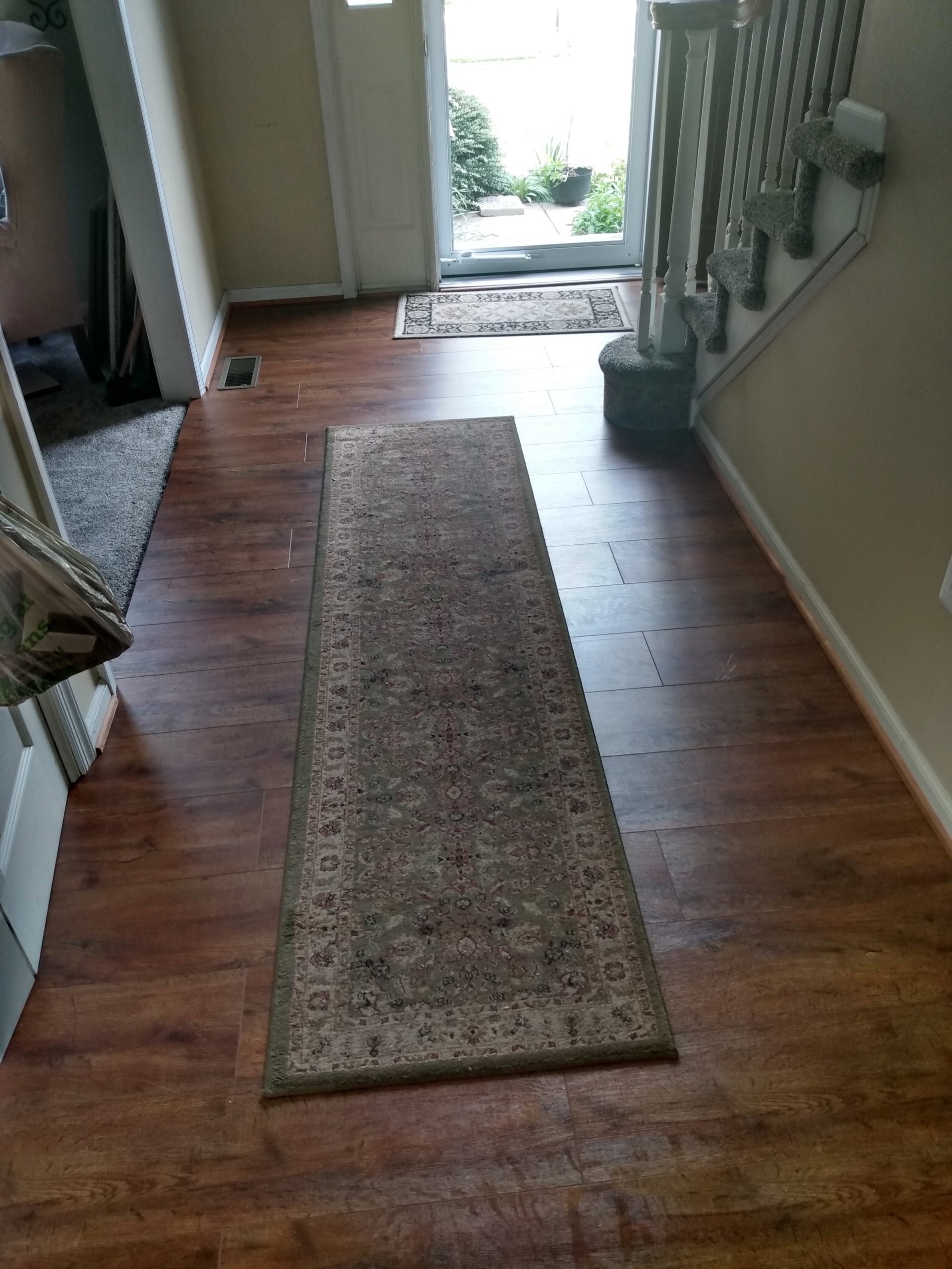 Finished wood-look flooring running down a hallway with a runner rug