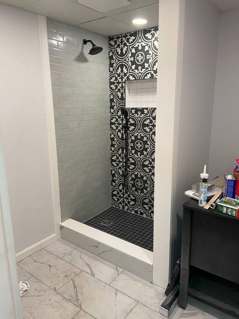 Walk-in shower with white subway tile and a black-and-white patterned accent wall