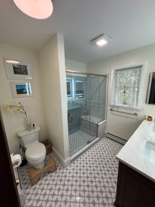Full bathroom with glass shower enclosure, patterned tile floor, and stone vanity