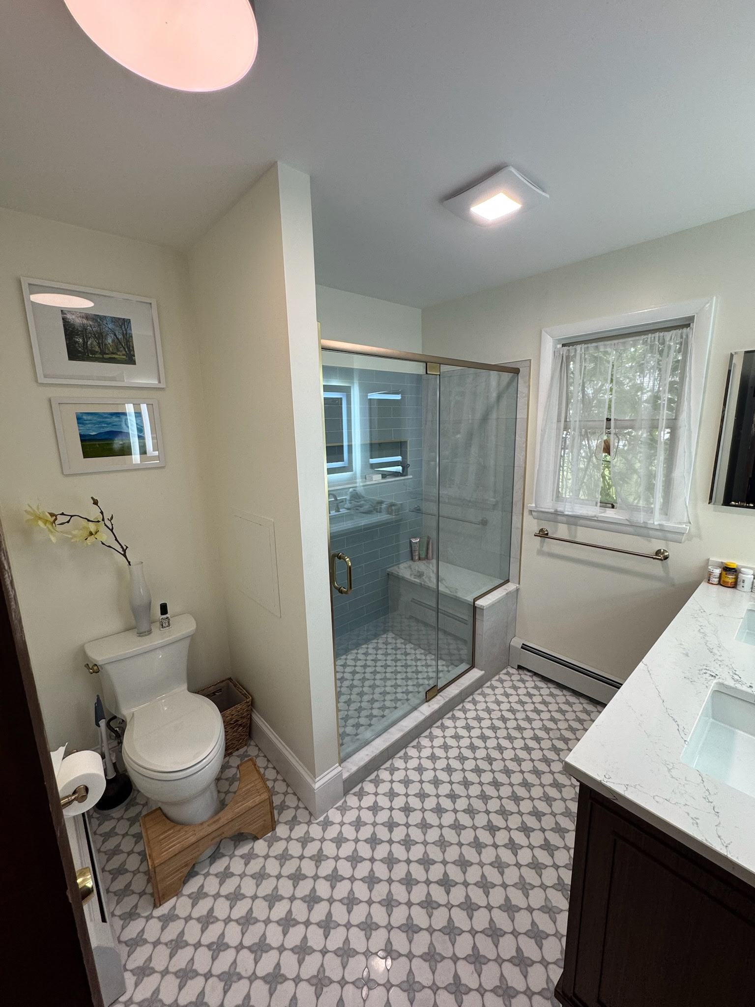 Full bathroom with glass shower enclosure, patterned tile floor, and stone vanity