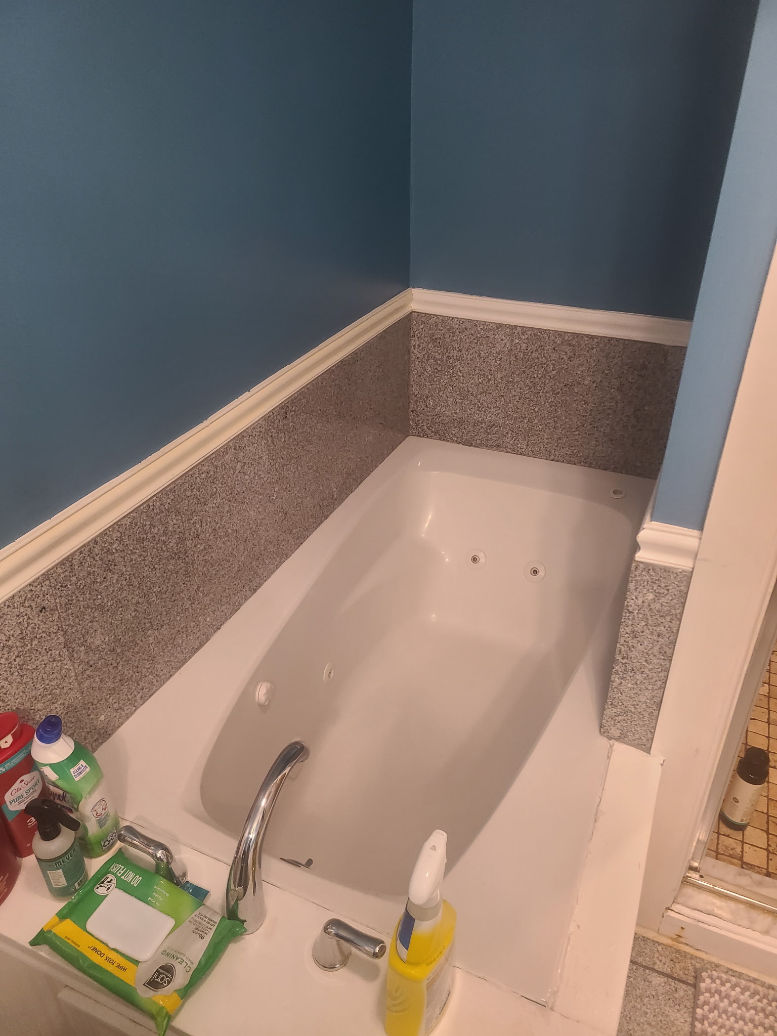 Jetted tub with a stone-look surround against a blue wall