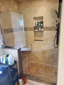 Walk-in shower before remodel with travertine tile, granite bench and framed glass door