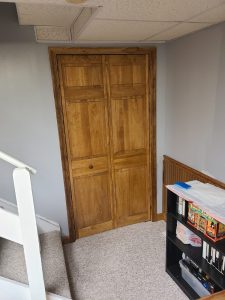Stained wood bi-fold closet doors and matching trim installed in a finished basement