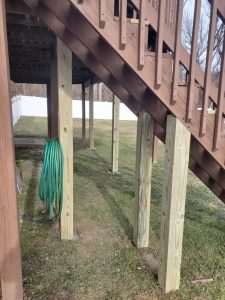 New pressure treated support posts replacing old posts under a raised deck