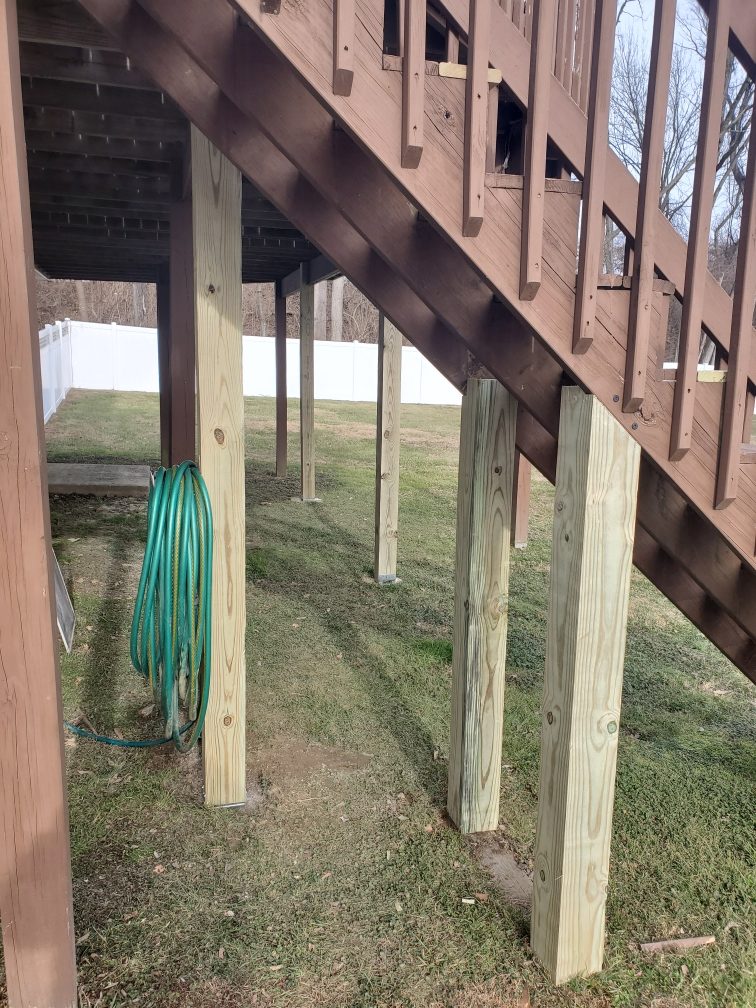 New pressure treated support posts replacing old posts under a raised deck