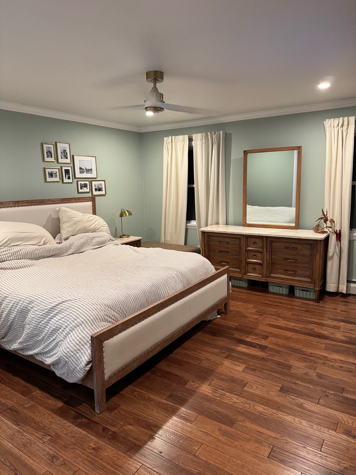 Finished bedroom with sage green walls, crown molding and new hardwood flooring