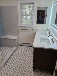 Double vanity with quartz countertop, brushed gold faucets and a backlit mirror