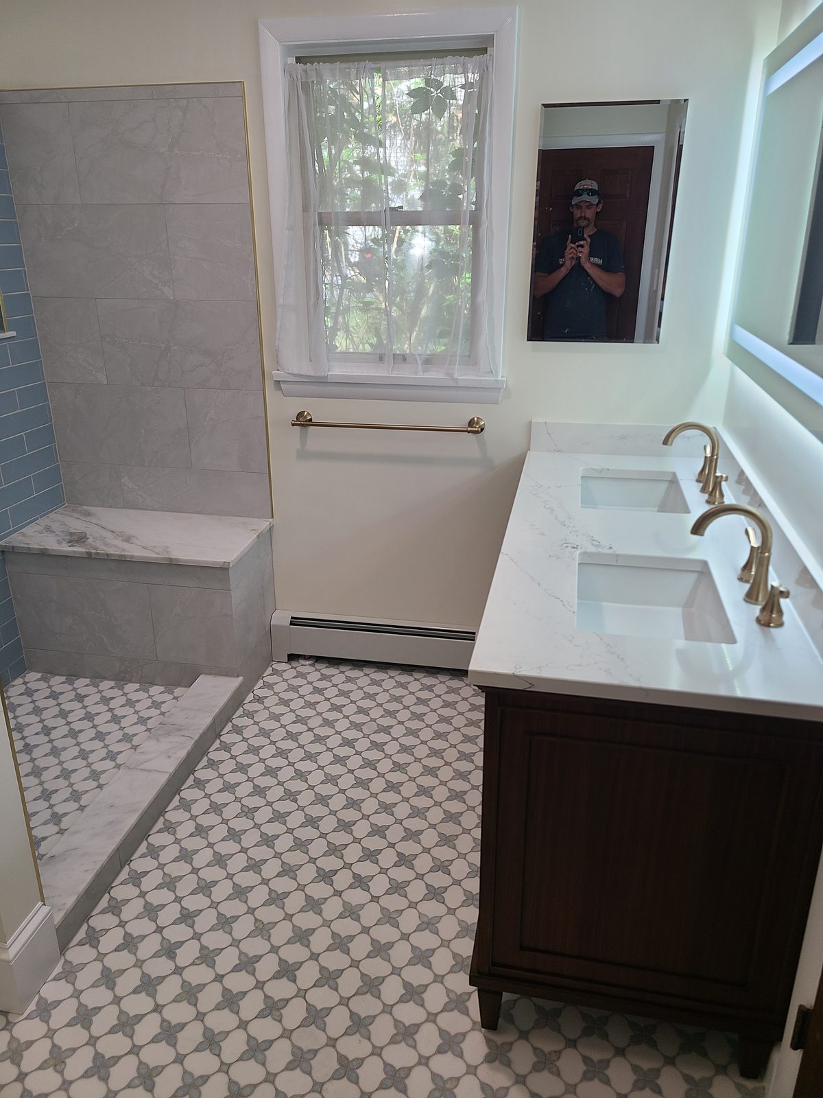 Double vanity with quartz countertop, brushed gold faucets and a backlit mirror