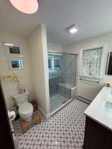 Remodeled bathroom with a glass walk-in shower, patterned floor tile and a quartz topped vanity