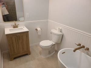 Remodeled bathroom with a wood vanity, beadboard wainscoting and a freestanding soaking tub