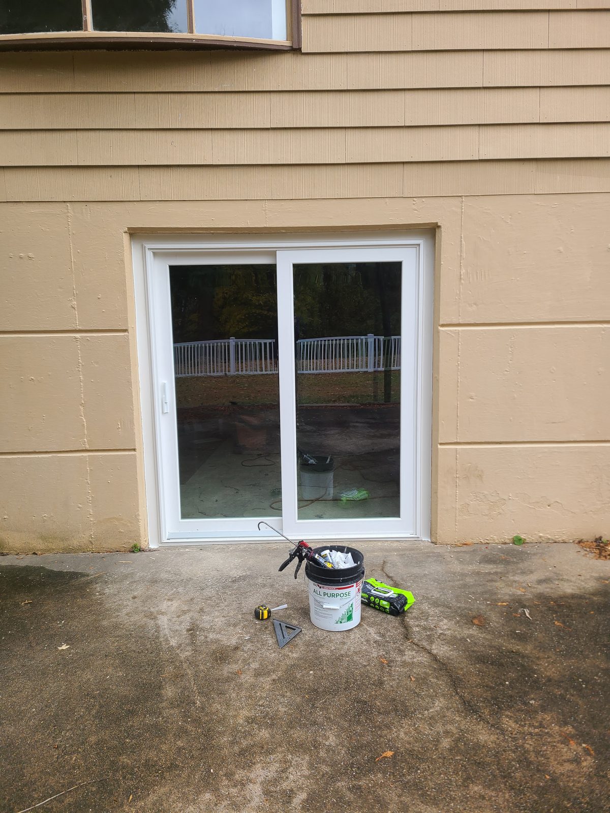 New white vinyl sliding patio door installed in a lower level exterior wall