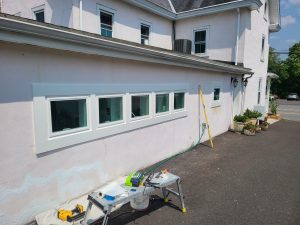 Row of five replacement windows with new exterior trim on a commercial stucco building
