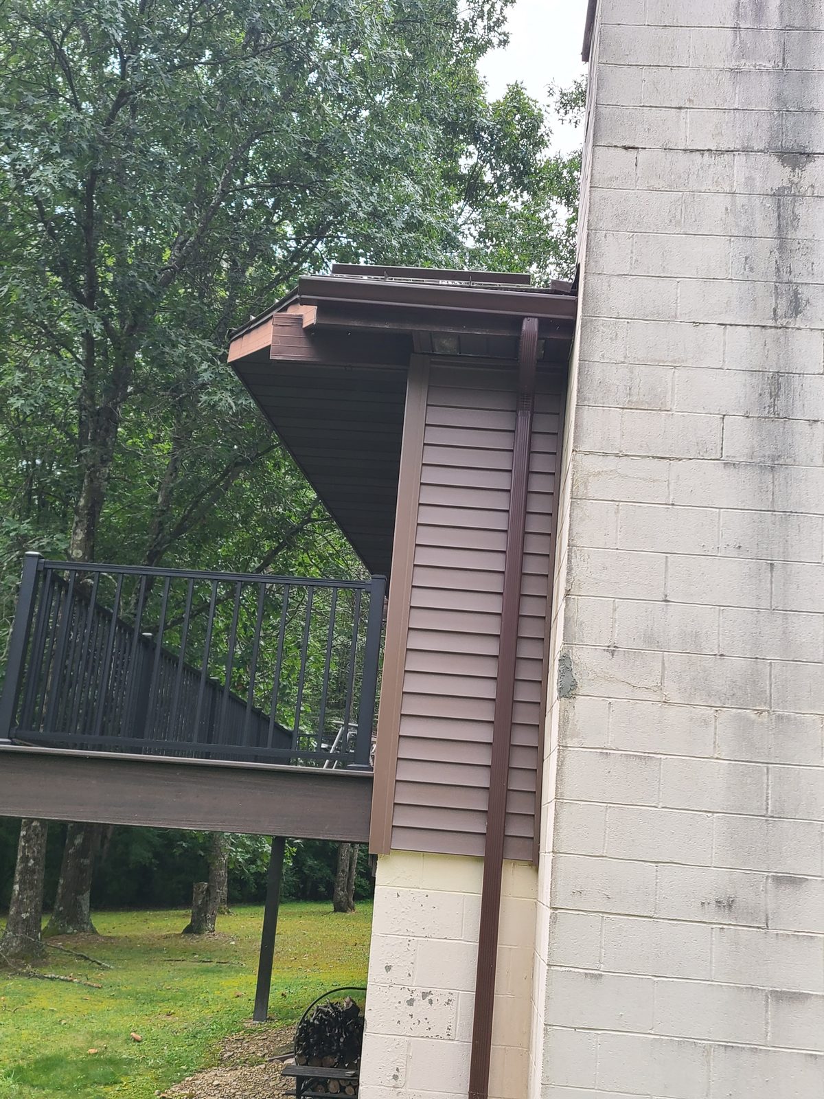 New brown vinyl siding with a new gutter and downspout at the chimney wall