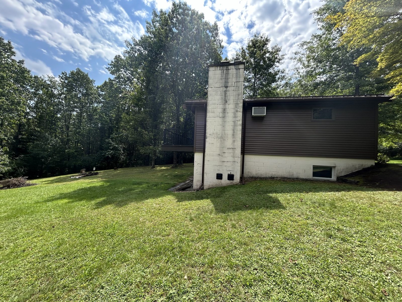 Rear exterior of the house with its original dark siding and block chimney