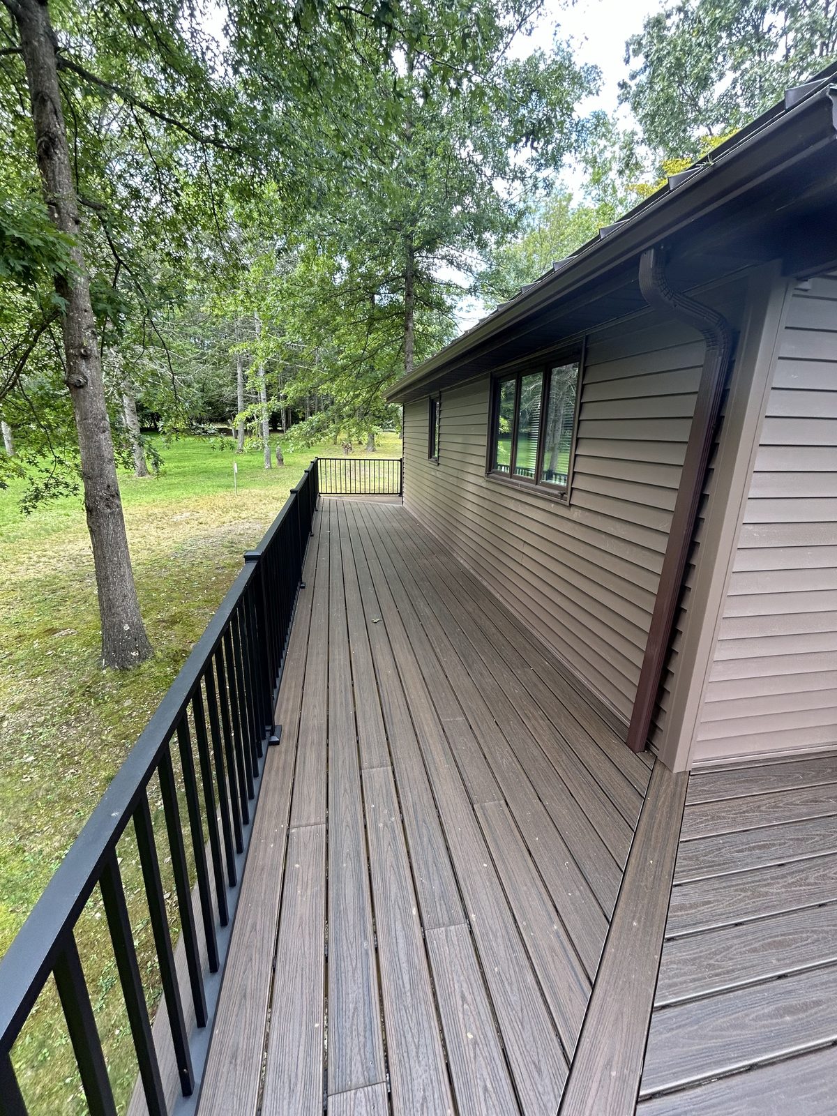 Composite deck walkway with black aluminum railing running along the side of the house