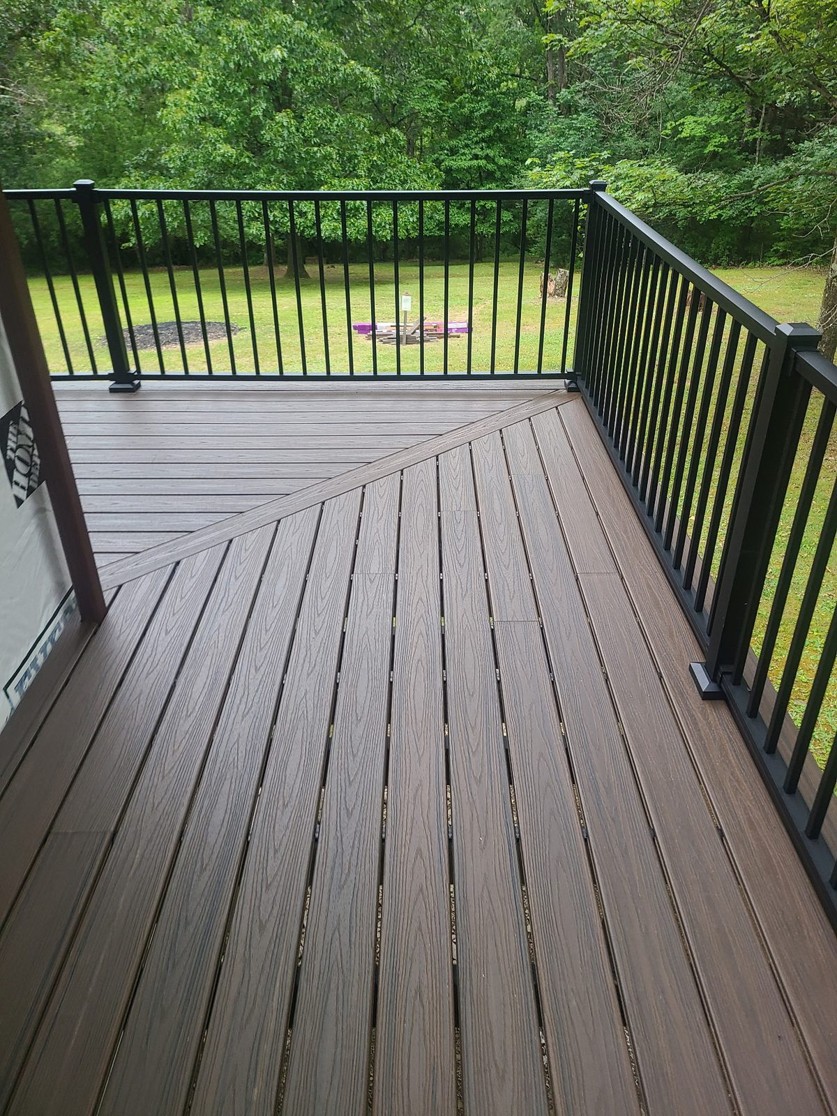 New composite deck boards with black aluminum railing overlooking the back yard