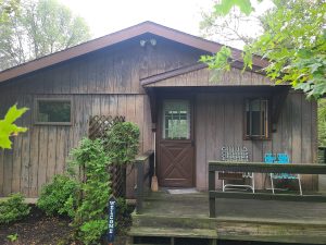 Front of the house before residing, with weathered board siding and a covered entry over the deck