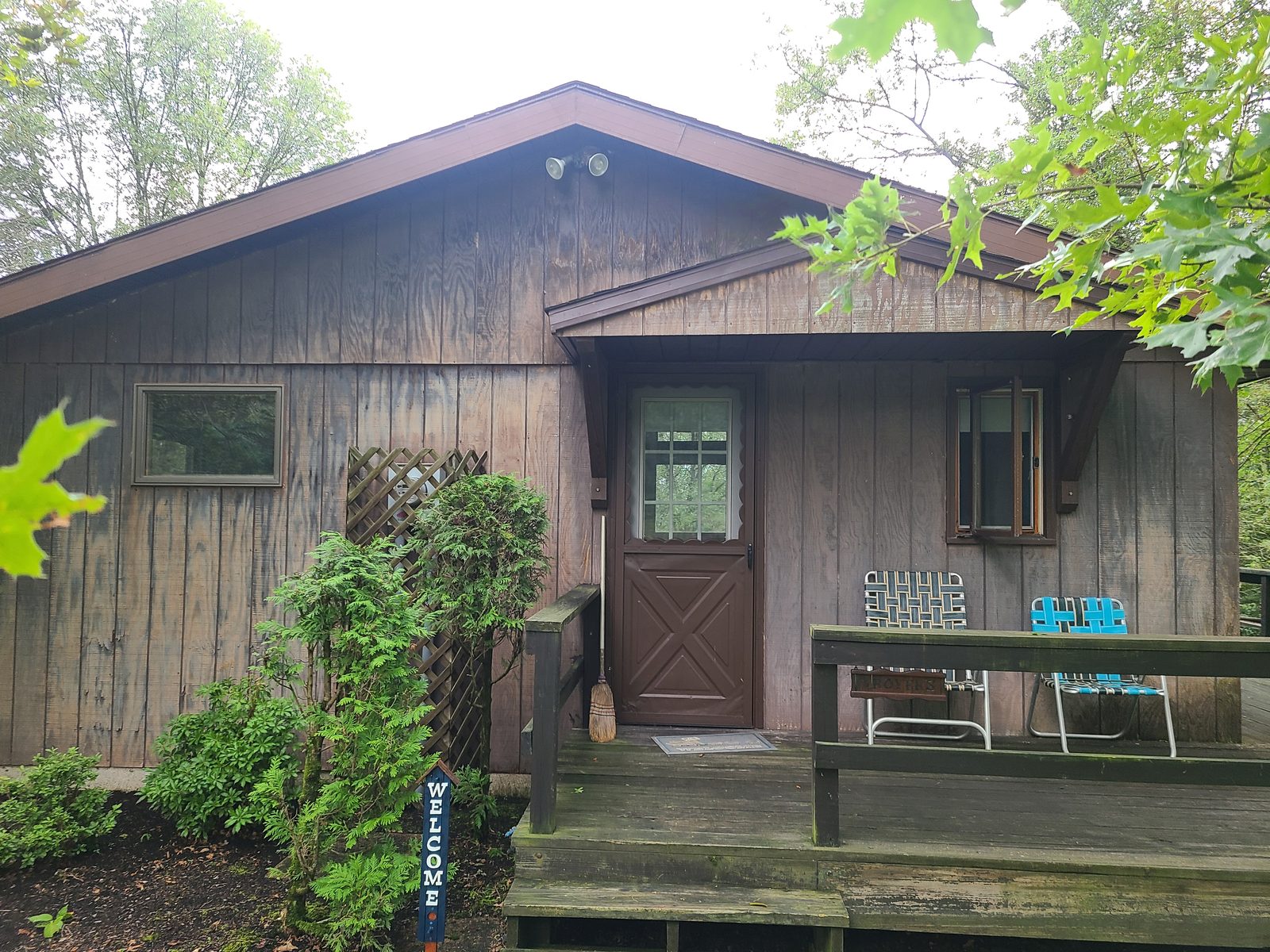 Front of the house before residing, with weathered board siding and a covered entry over the deck