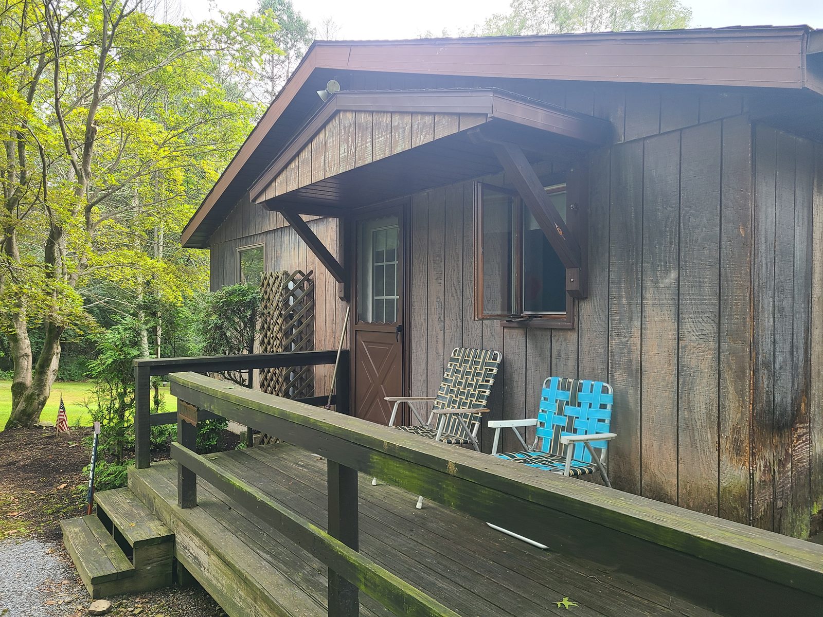Entry deck and ramp before the exterior was redone, with weathered siding and an old wood railing