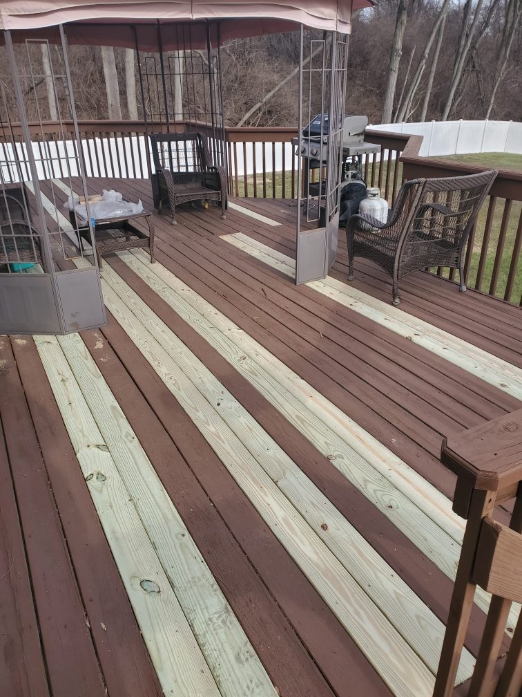 New pressure treated deck boards woven in among existing stained boards during a deck rebuild